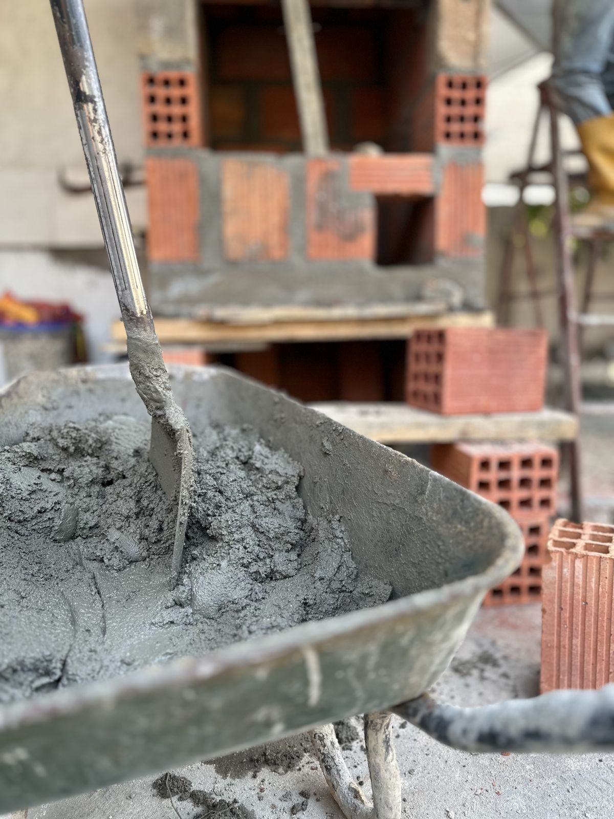Carrinho de mão com argamassa e tijolos em obra